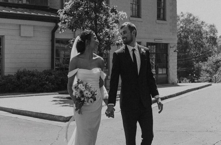 Сouple wearing a white gown and a black suit with a dog