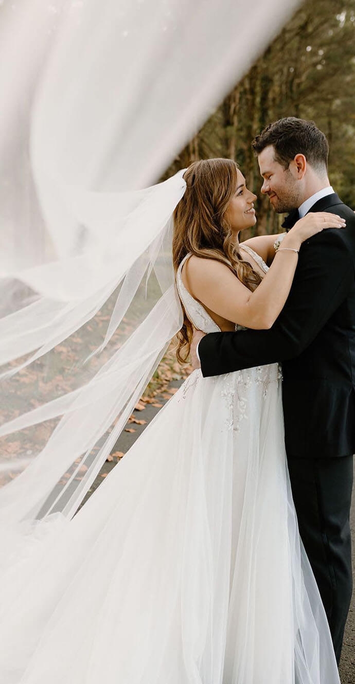 Сouple wearing a white gown and a black suit with a dog